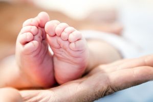 Man holding a newborn by his feet â?? purity concepts
